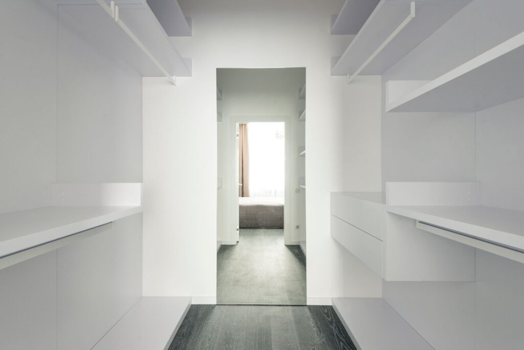Bright and spacious modern minimalist walk-in closet with open shelving.