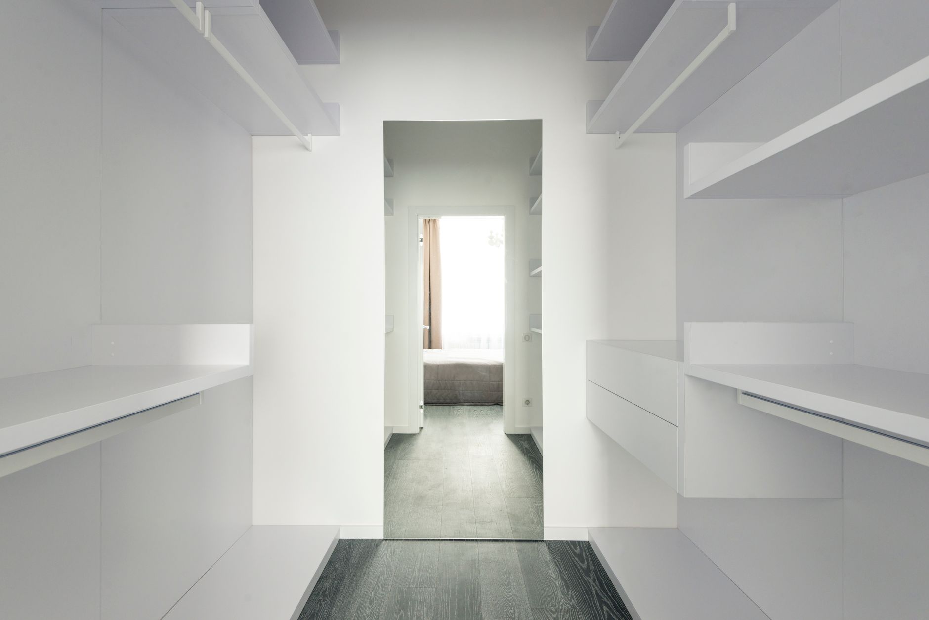 Bright and spacious modern minimalist walk-in closet with open shelving.