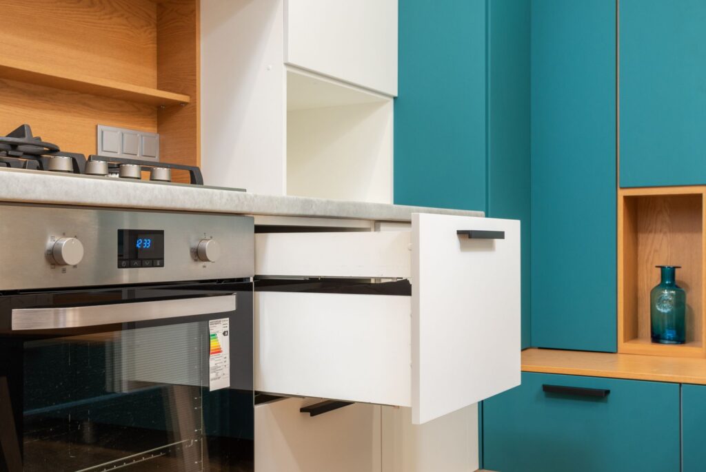 Contemporary oven with sticker and gas stove under wooden shelves in kitchen with open drawer