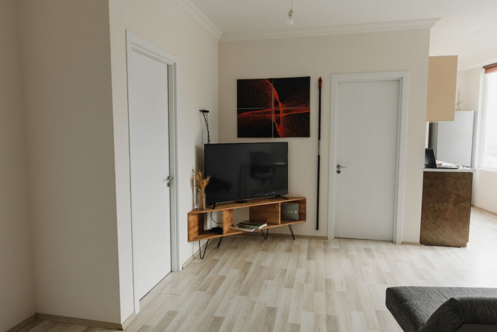 A modern minimalist living room with TV, wall art, and a wooden floor, offering a clean and organized look.